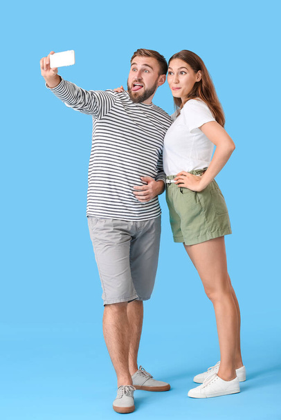 Νεαρό ζευγάρι που παίρνει selfie στο φόντο χρώμα - Φωτογραφία, εικόνα