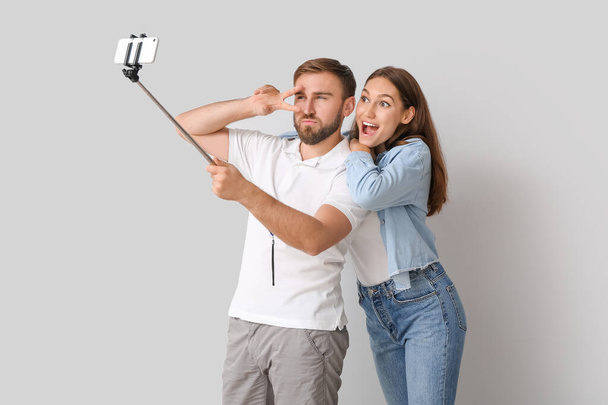 Young couple taking selfie on light background - Foto, afbeelding
