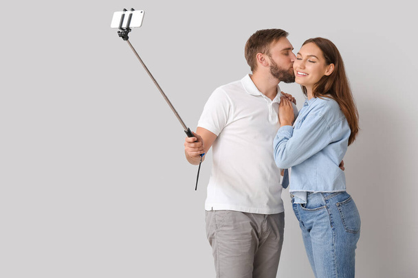 Young couple taking selfie on light background - Φωτογραφία, εικόνα
