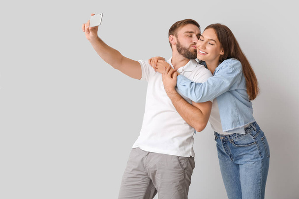 Young couple taking selfie on light background - Zdjęcie, obraz
