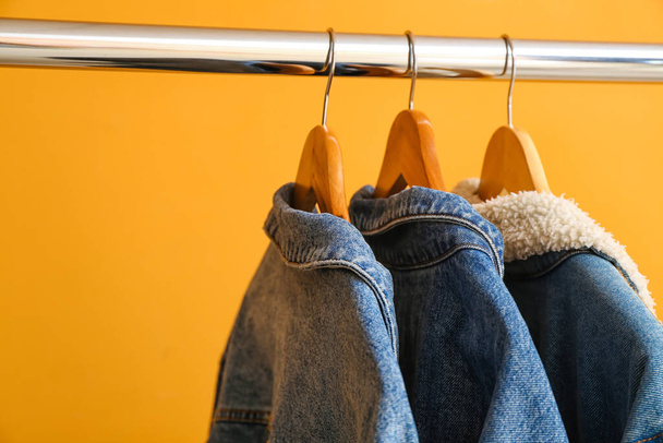 Rack with jeans clothes on color background - Photo, Image