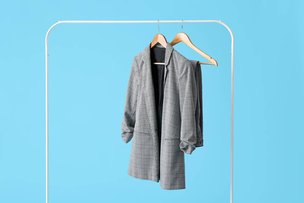 Rack with clothes on color background - Foto, afbeelding