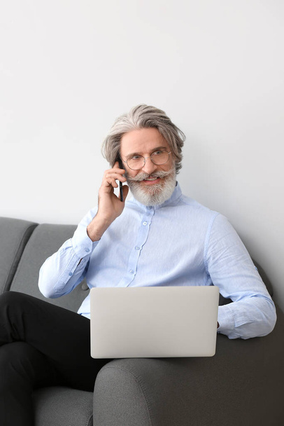 Vezető üzletember portréja laptoppal és mobiltelefonnal az irodában - Fotó, kép