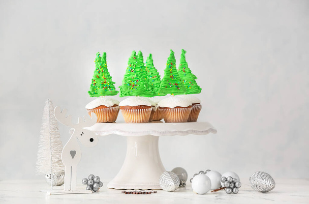 Stand with tasty Christmas cupcakes on table - Photo, image