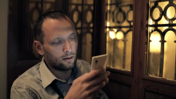 Undecided man with smartphone - Video, Çekim
