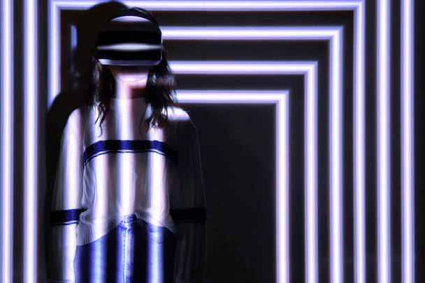 Woman using virtual reality headset, moving hand at interactive technology exhibition with multicolor projector light illumination, immersive concept - Photo, Image