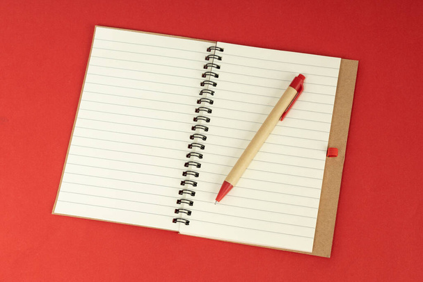 Σύνολο χαρτί ανακύκλωσης σημειωματάριο και στυλό. Άνοιγμα σημειώματος ημερολογίου σε κόκκινο φόντο - Φωτογραφία, εικόνα