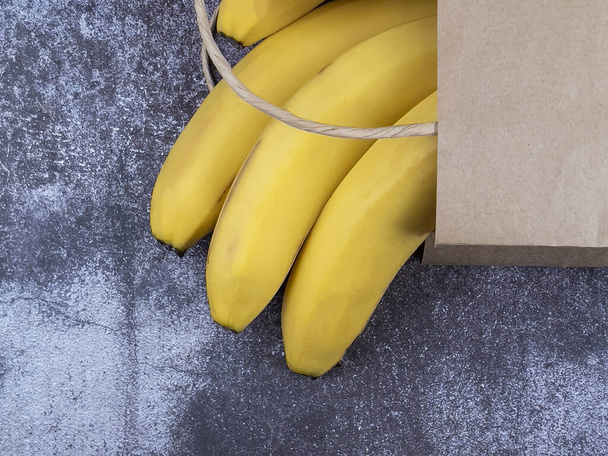 Bunch of bananas in a paper bag on the table - Foto, imagen