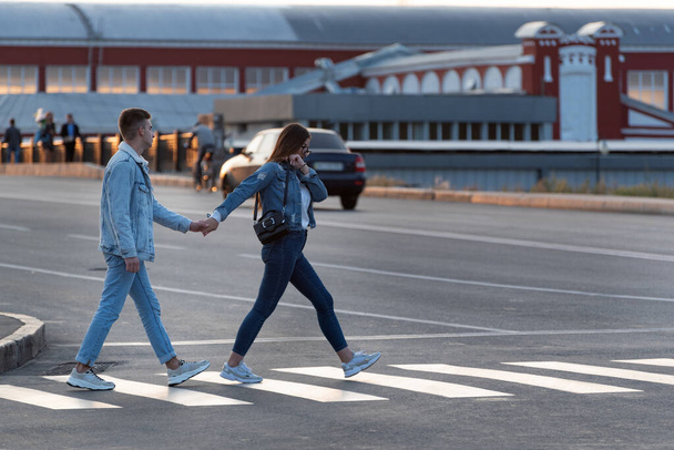 Una ragazza e un ragazzo attraversano la strada per mano. Sempre insieme. - Foto, immagini