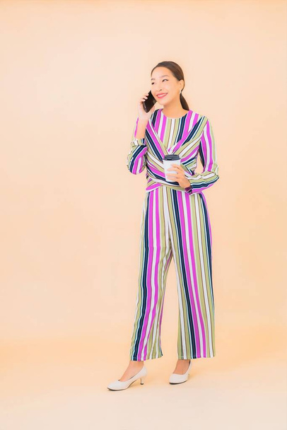 Portrét krásná mladá asijská žena používat chytrý mobilní telefon na barevném izolovaném pozadí - Fotografie, Obrázek
