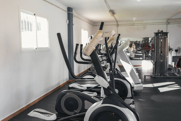 Photographie d'une salle de gym avec des appareils d'exercice. Elliptiques, tapis de course. - Photo, image