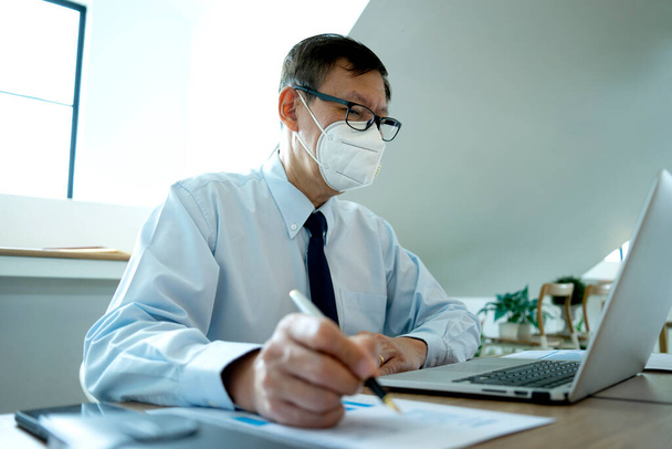 Businessman working in the office he protects himself from the virus covid-19 by use the face mask image focus at the work hand. - Foto, immagini
