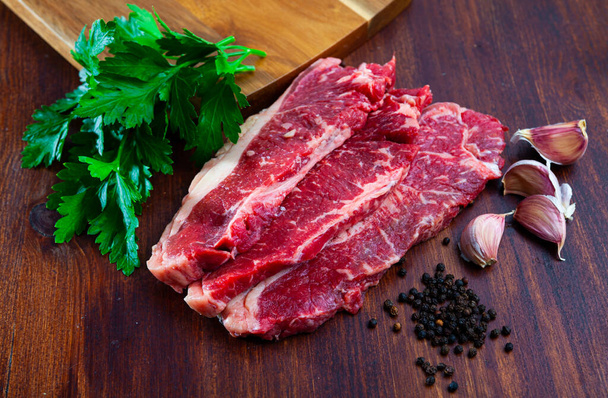 close up of pieces of marbled beef served with parley on wooden table - Foto, imagen