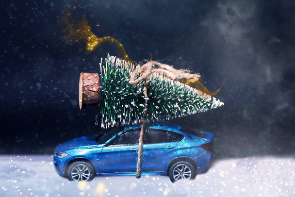Sinisessä henkilöautossa on joulukuusi sidottuna kattoon sumussa. Sen lumi.Joulu käsite - auton ajo joulukuusi kaunis perhe joulu. - Valokuva, kuva
