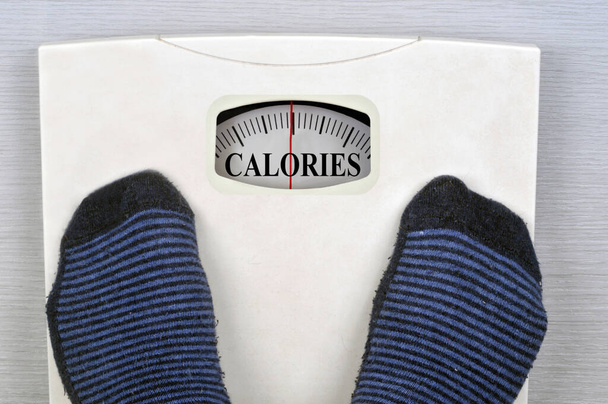 Person weighing scale showing calories in close up  - Photo, Image