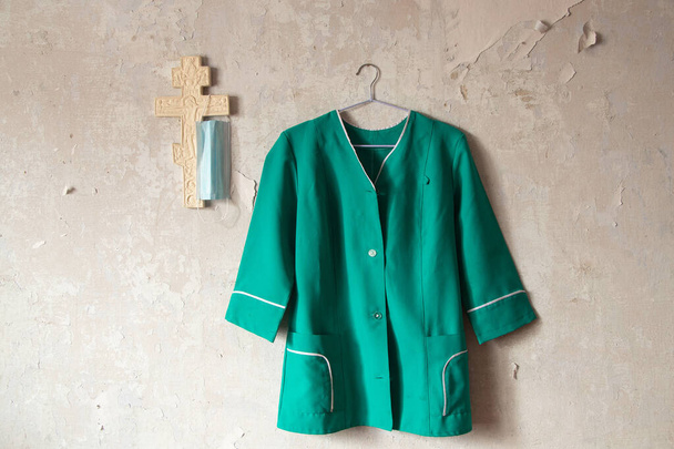 Ukraine nurse costume hanging on a white old wall near a plaster Christian cross indoors - Photo, Image