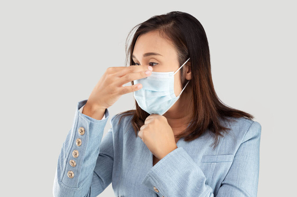 Азійська комерсантка в медичній масці, відокремленій на сірому фоні. - Фото, зображення