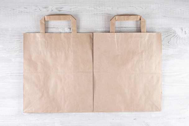 deux sacs en papier écologique marron sur une table en bois blanc. Place pour votre logo. - Photo, image