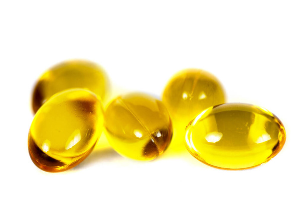 Cápsulas amarillas de vitamina D, macro primer plano de píldoras doradas aisladas en blanco - Foto, imagen