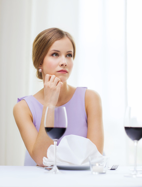 Upset woman with glass of whine waiting for date - Foto, Bild