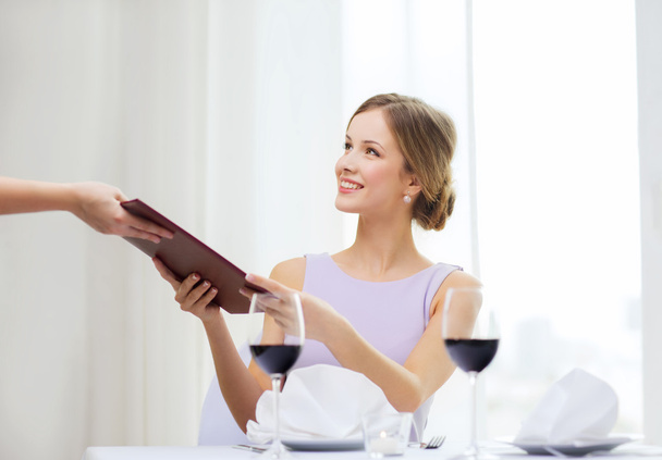 Smiling woman giving menu to waiter at restaurant - Fotografie, Obrázek