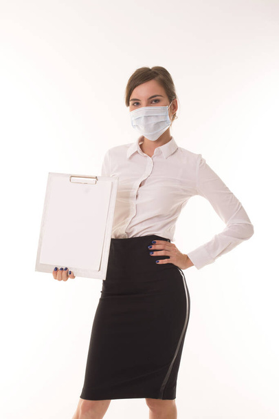 Chica de pie en una máscara médica y sostiene una tableta. - Foto, Imagen