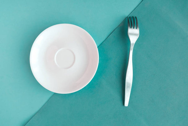 Empty plate and fork on color geometric background, minimal concept, copy space for the text - Foto, afbeelding
