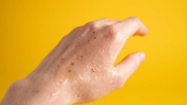 Scrub gel applied on girl hand. Yellow background. Skin care concept. Young woman applying natural scrub on hands - Photo, Image
