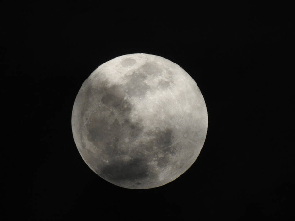 Close up of Real and Natural Full Moon in the Sky at night at Bangalore, Karnataka, India in a black background - Фото, изображение