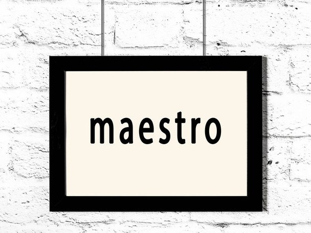 Schwarzer Holzrahmen mit Inschrift Maestro hängt an weißer Ziegelwand  - Foto, Bild