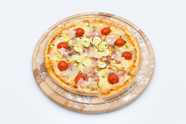 Viande entière Pizza au style salade César sur planche de bois servie avec farine culinaire, isolée sur fond blanc. Plat aux tomates cerises tomates, poulet, bacon, parmesan, oeufs de caille - Photo, image