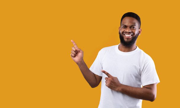 Cheerful African Man Pointing Fingers Aside Standing Over Yellow Background - Photo, Image