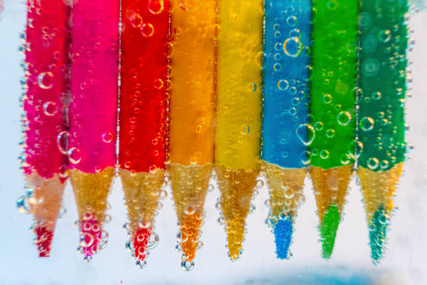 a row of colored pencils in sparkling water - Photo, Image