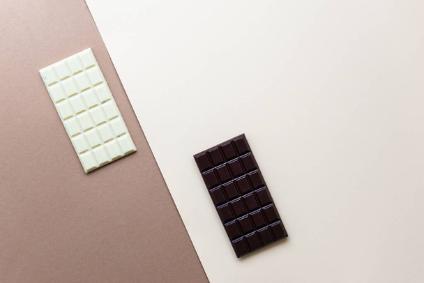 Батончики білого і темного шоколаду на коричневому фоні. Цукор, глютен, без лактози
. - Фото, зображення