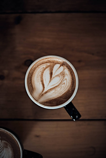 šálek horké kávy latte art na dřevěném stole, zaměření na bílé foa - Fotografie, Obrázek