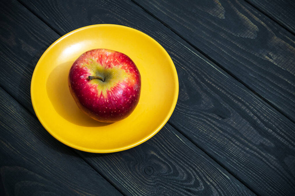 Ένα μήλο σε ένα πορτοκαλί πιάτο. Η ιδέα της νηστείας μετά τις γιορτές - Φωτογραφία, εικόνα