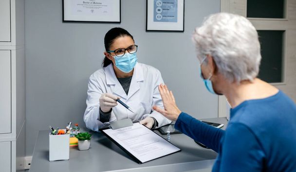 Női beteg, aki megtagadja a coronavirus vakcinához szükséges beleegyező nyilatkozat aláírását - Fotó, kép