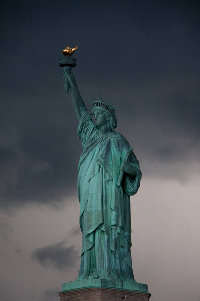 Postales de Nueva York: Estatua de la Libertad contra el cielo oscuro y nublado, Isla de la Libertad, vista desde el ferry - Foto, imagen