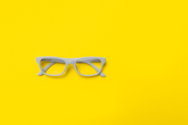 Grey glasses on a yellow background. Top view, space for your text. - Foto, immagini