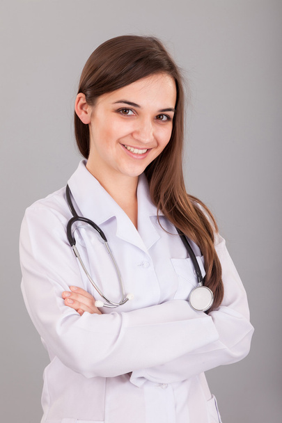 Young and beautiful nurse on a grey - Foto, afbeelding