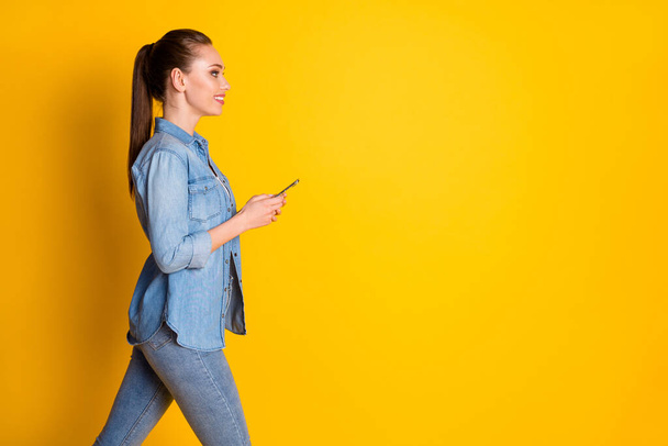 Profile side photo of positive cheerful girl go walk copyspace use smartphone texting typing follow post comment wear casual style clothes isolated over bright shine color background - Foto, immagini