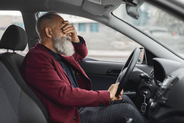 Exhausetd aged grey-haired man having headache while driving car - Photo, Image