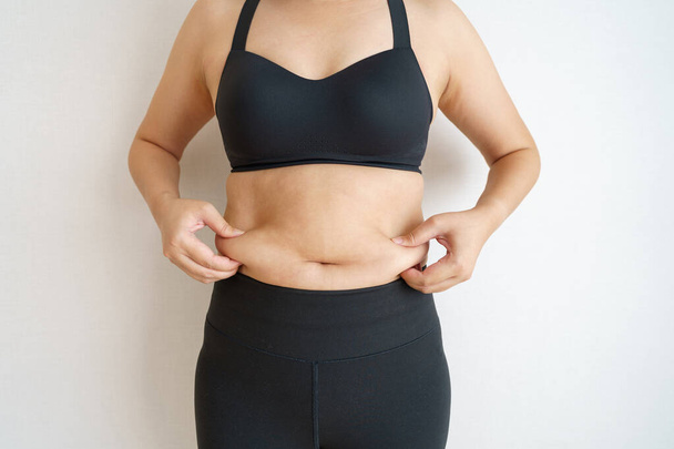 Women body fat belly. Obese woman hand holding excessive belly fat. diet lifestyle concept to reduce belly and shape up healthy stomach muscle. - Photo, Image