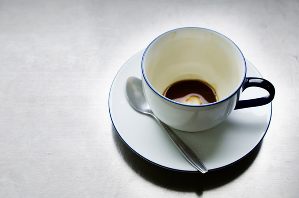 Порожня чашка кави з ложкою на фоні металевої пластини
 . - Фото, зображення