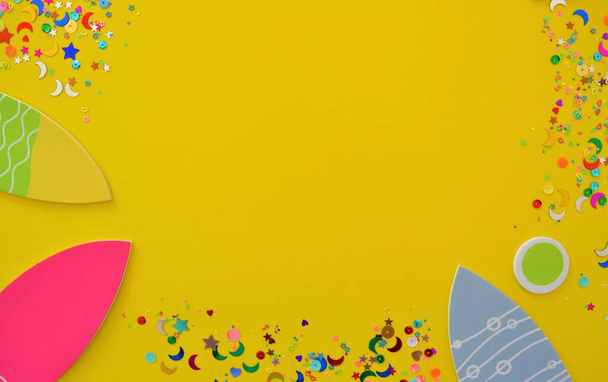 Invitation for a birthday or a beach party consisting of several fish and bubbles surrounded by confetti and sequins on a yellow background - 写真・画像