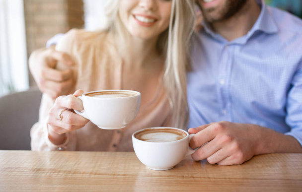 Cropped view of romantic couple drinking coffee and hugging at cafe - Photo, Image