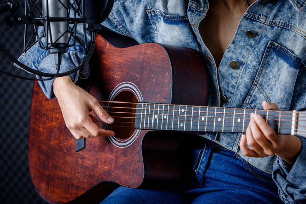 Chiudi le dita della donna che tiene il mediatore con una chitarra che registra una canzone in studio di registrazione - Foto, immagini