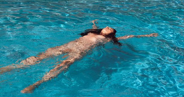 Naked woman outdoors. Beautiful young nude woman in swimming pool. - Foto, imagen