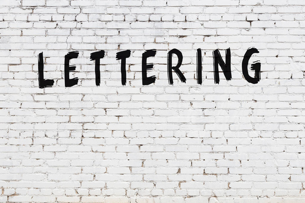 Inscrição lettering escrito com tinta preta na parede de tijolo branco. - Foto, Imagem
