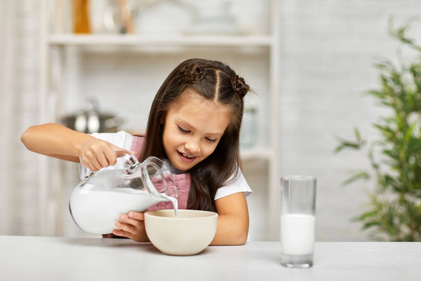 cute little girl eating breakfast: cereal with the milk - Fotó, kép